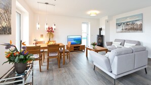 Una sala de estar moderna con sofá, mesa de comedor, sillas y televisor.