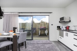 A modern kitchen with a dining area, a sliding glass door to the backyard, and a microwave on the countertop. - Kings On Peace (Rotorua)