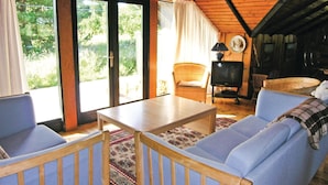 Una sala de estar acogedora con techo de madera, un sofá, una mesa y un televisor.