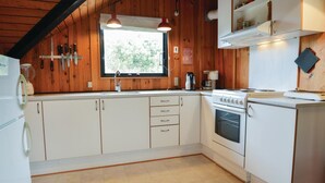 Una cocina con paredes de madera, una ventana, un lavamanos, una estufa y armarios.