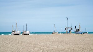 Varias embarcaciones fondeadas en una playa arenosa con un mar tranquilo al fondo.