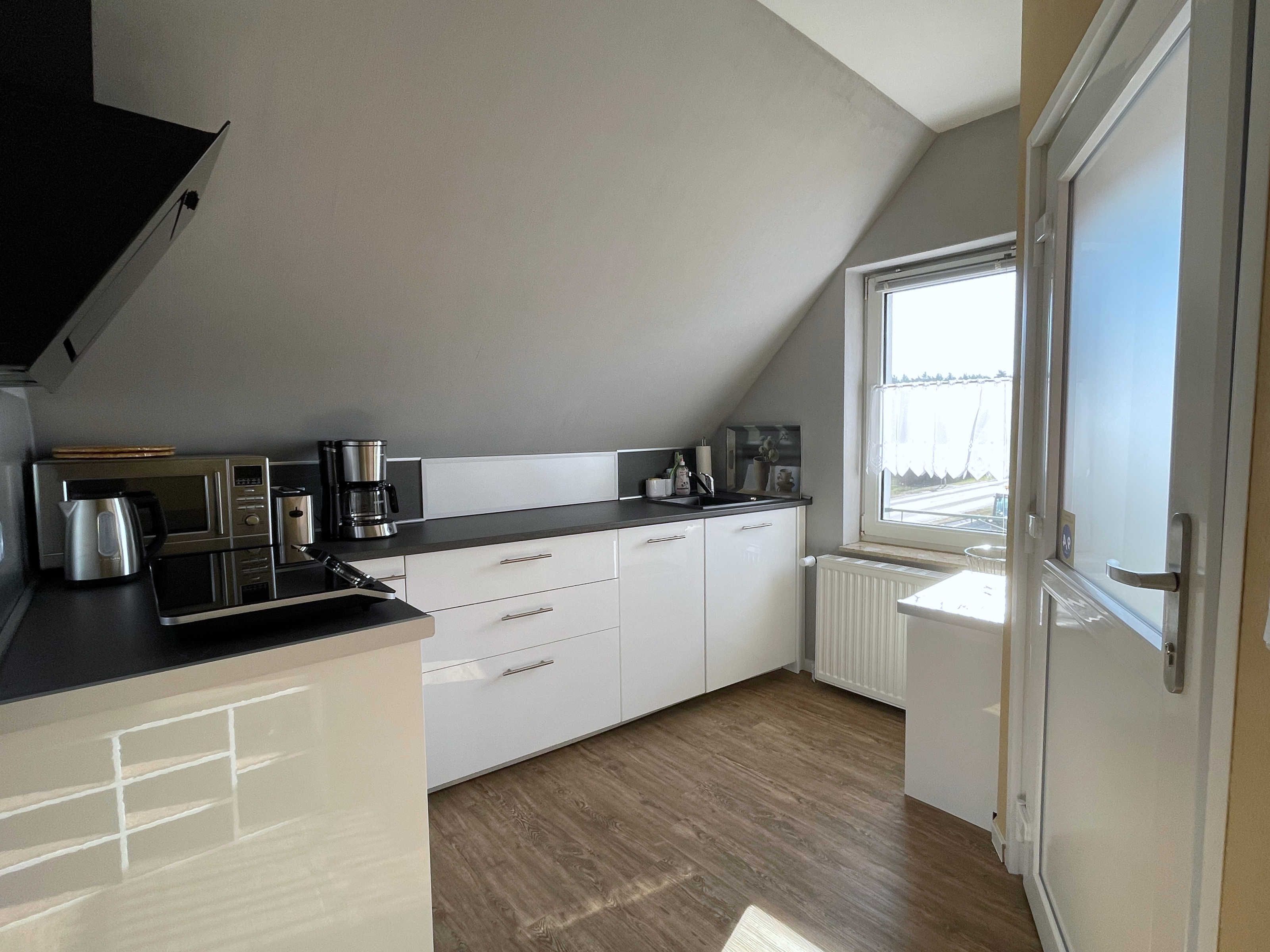 A modern kitchen with white cabinets, a black countertop, and a window providing natural light.