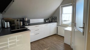 Eine moderne Küche mit weißen Schränken, einer schwarzen Arbeitsplatte und einem Fenster, das für natürliches Licht sorgt.
