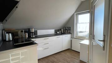 A modern kitchen with white cabinets, a black countertop, and a window providing natural light.
