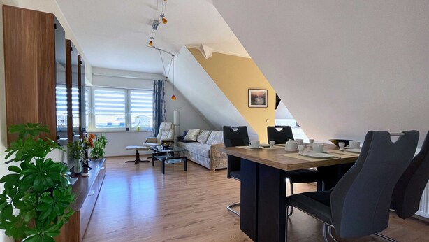 Eine moderne Loftsage mit Essbereich, einer Couch und einem großen Fenster.