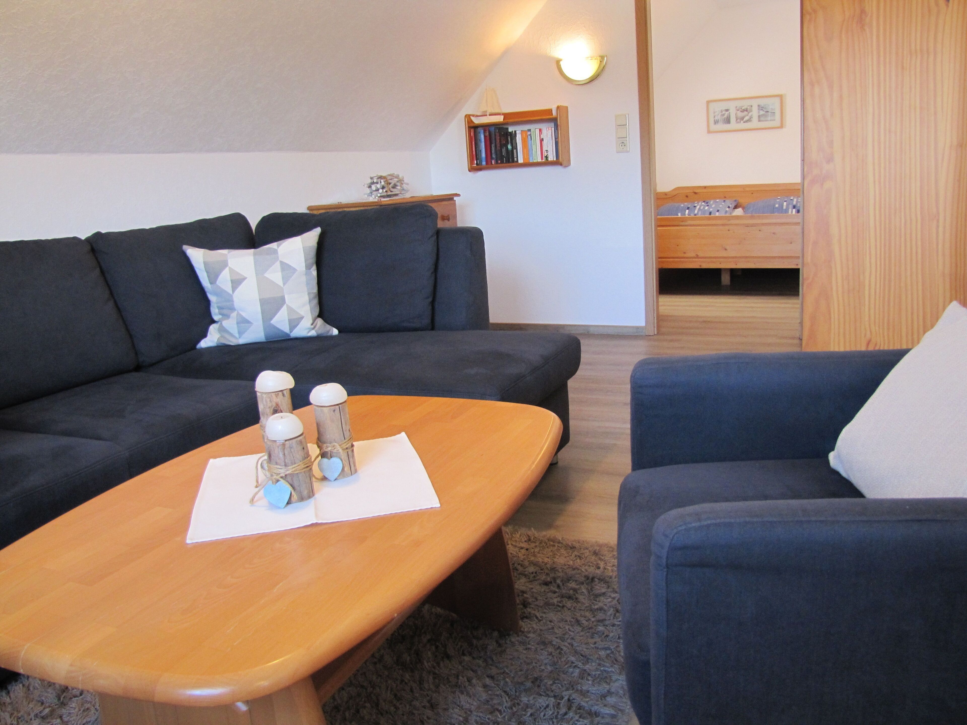 A modern living room with a dark blue sofa, a wooden coffee table, and a blue armchair.