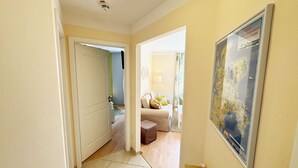 A hallway with a door leading to a living room, a framed map on the wall, and a radiator.