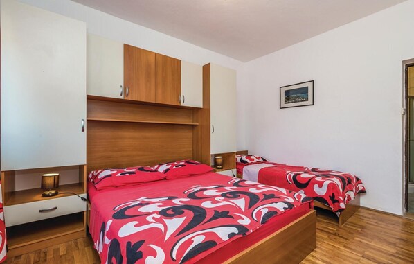 Ein Schlafzimmer mit zwei Betten, einem Holzschrank und einem gerahmten Bild an der Wand.