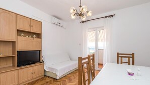 Habitación pequeña con cama, televisor, muebles de madera y una mesa de comedor.