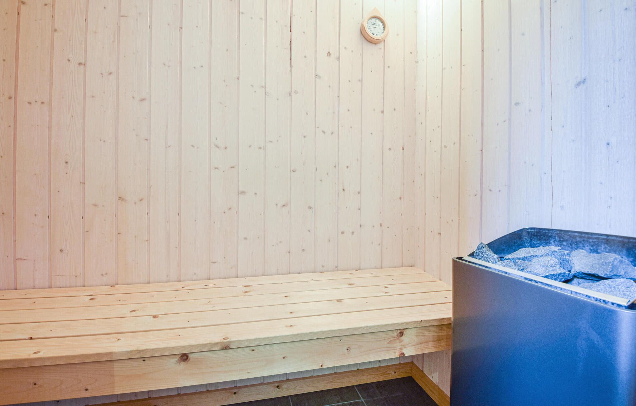 Un espai de sauna amb seients de fusta i un recipient metàllic gran, probablement per a gel o aigua.