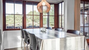 A dining area with a large table, chairs, and a hanging light fixture.
