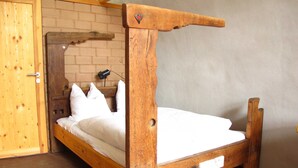 Un lit à baldaquin en bois avec une tête de lit, un mur en briques et une porte en bois.