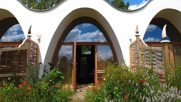 Un bâtiment doté d’une toiture ondulée originale et de fenêtres en arc de cercle.