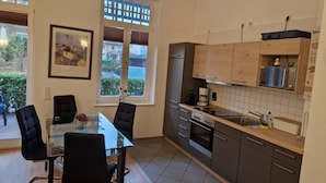 Eine moderne Küche mit Esstisch und Stühlen, inklusive Kühlschrank, Backofen und Kaffeemaschine.