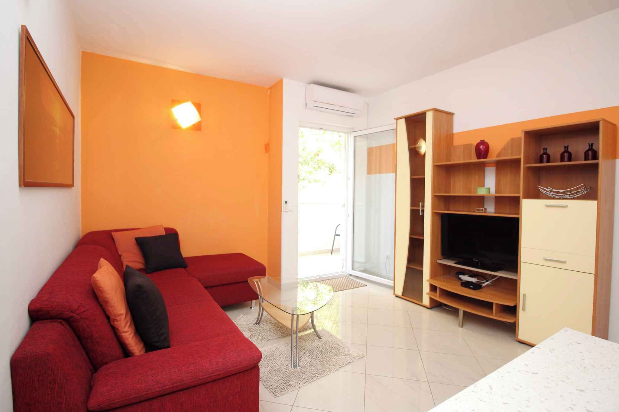 A modern living room with a red sofa, a glass coffee table, and a wooden entertainment unit.