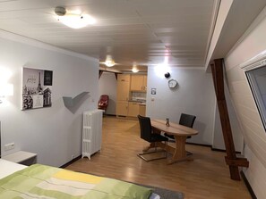 A compact living space with a dining area, kitchenette, and a radiator.