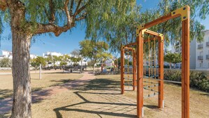 A playground with swings and climbing structures, surrounded by trees and a clear sky. - Nice apartment in Roldán with WiFi (Roldán)