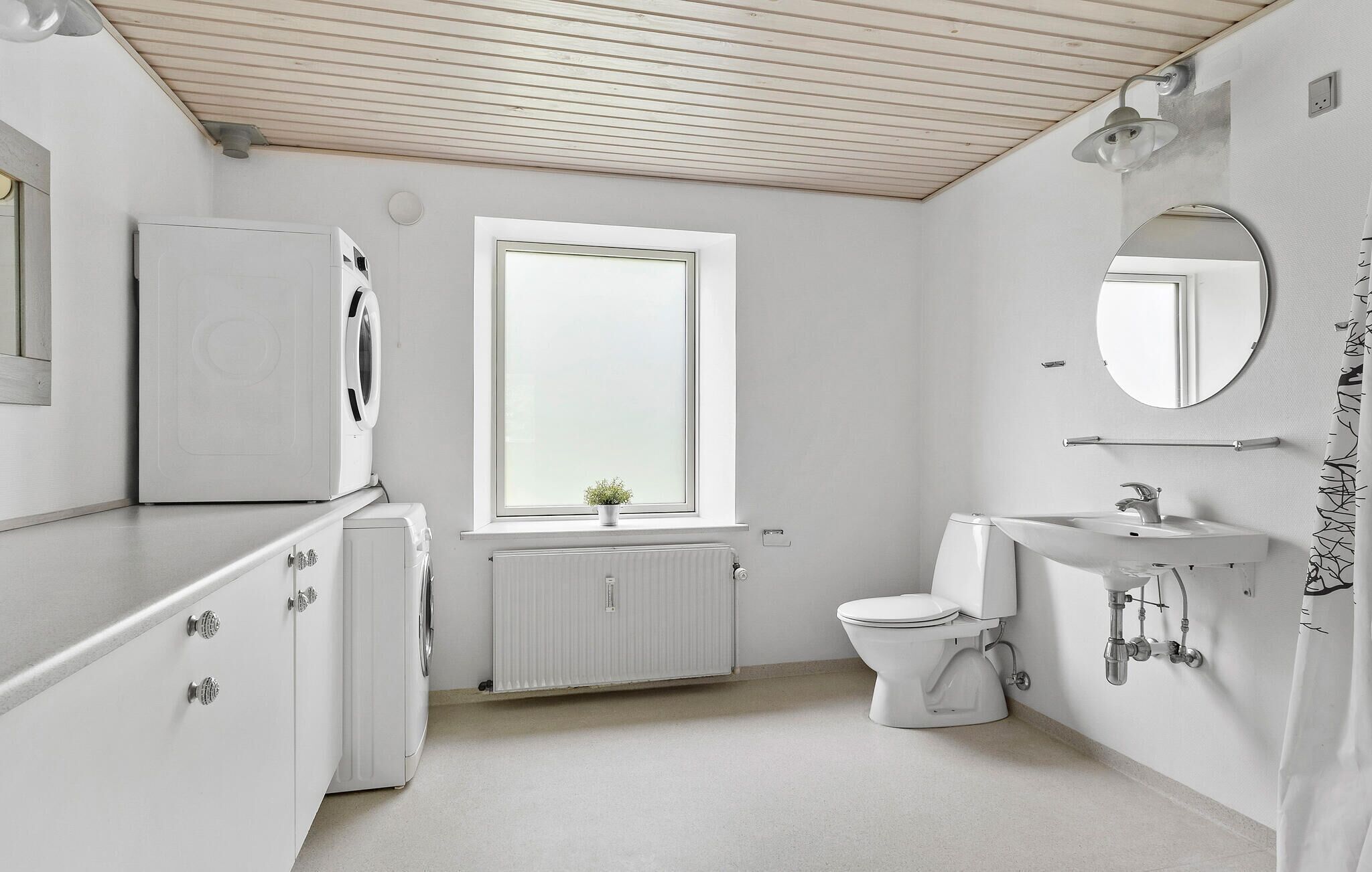 Une salle de bain moderne équipée de toilettes, d’un lavabo et d’un lave-linge encastré.