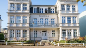 Ein zweistöckiges Gebäude mit Balkon und einem zentralen Eingang, mit dem Schild 'Villa Ahlbeck'.