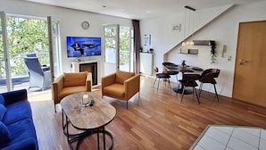 Ein modernes Wohnzimmer mit Fernseher, Sofa und Essbereich.