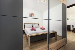 Een moderne slaapkamer met een houten bed, een nachtkastje en een spiegel.