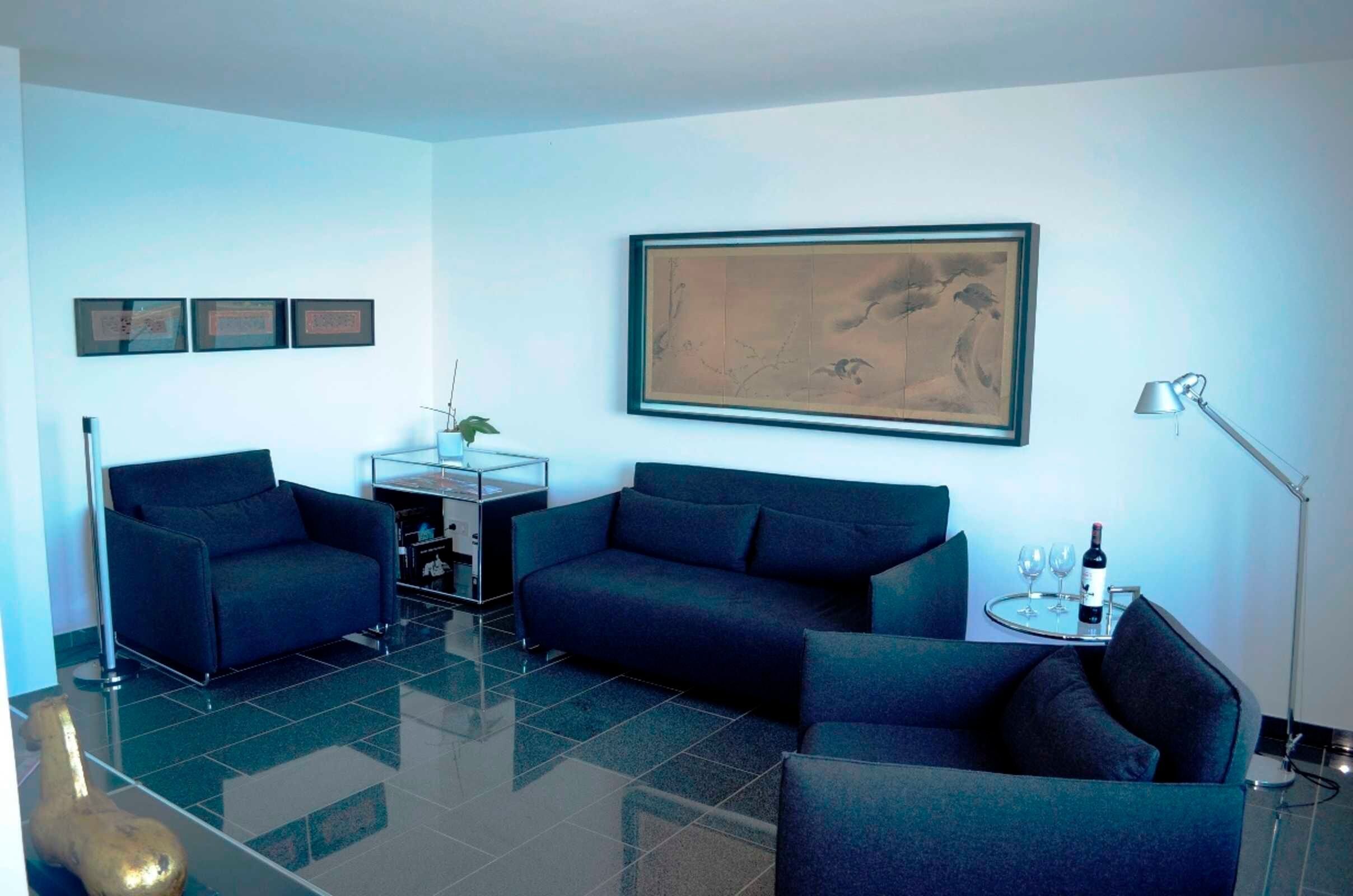 A modern living room with two sofas, a coffee table, a lamp, and framed artwork on the wall.