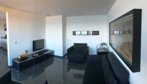 A modern living room with a flat-screen TV, a sofa, a coffee table, and a framed picture on the wall. - Sino Suite, 2. OG, balcony seafront, - Dünenblick Apartments (Helgoland)
