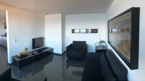 A modern living room with a flat-screen TV, a sofa, a coffee table, and a framed picture on the wall. - Sino Suite, 2. OG, balcony seafront, - Dünenblick Apartments (Helgoland)