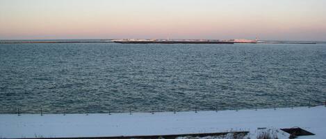 A snowy landscape with a body of water and a distant shoreline.