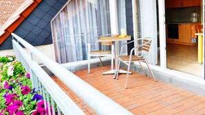 A balcony with a table and chairs, a railing, and a view of the interior kitchen. - Vacation apartment 1 - 55 sqm (2-4 persons), balcony - Weichaer Hof FBS Sonja Fritsch (Weißenberg)