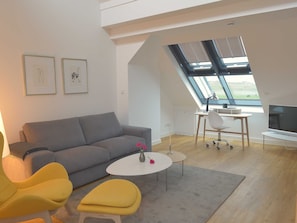 A modern living room with a grey sofa, a yellow chair, a white coffee table, and a skylight. - Apartment 08 - gate to the sea (Helgoland)