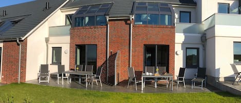 En moderne bygning med murstensfacade, store vinduer og et fladt tag med ovenlysvinduer.