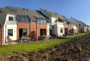 Een rij moderne huizen met platte daken, grote ramen en buitenplaatsen.