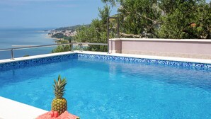 Una piscina amb vista al mar, una pinya i rodanxes de meló.