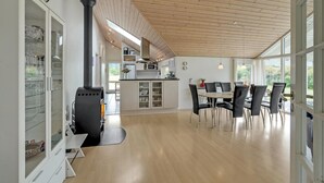 Une cuisine moderne dotée d’un îlot central, d’un plafond en bois et de grandes fenêtres.