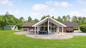 Une maison avec un patio couvert, un petit abri de jardin et un but de football.