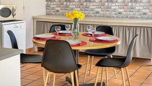 A dining area with a round table set for four, black chairs, a vase with yellow flowers, and a brick wall in the background. - Beautiful home in St. Pierre Langers (St. Pierre Langers)