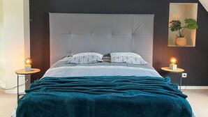 A modern bedroom with a tufted headboard, a teal throw blanket, and two bedside lamps. - Beautiful home in St. Pierre Langers (St. Pierre Langers)
