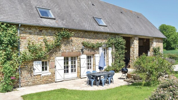 A stone building with a sloped roof, a patio with a table and chairs, and a barbecue grill. - Beautiful home in St. Pierre Langers (St. Pierre Langers)