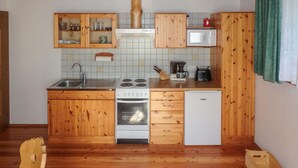 A compact kitchen with wooden cabinets, a stove, a sink, and a microwave.