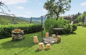 A garden with a fire pit, wooden stools, and a stone structure. - Ferienwohnung Klein St. Paul (Klein St. Paul)