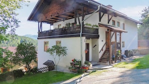 A two-story house with a balcony, a wooden staircase, and a small garden area.