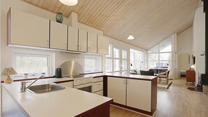 A modern kitchen with white cabinets, a stainless steel sink, and a wooden ceiling. - 4 bedroom awesome home in Hasle (Hasle)