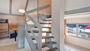 Un interior modern amb una escala de caragol, una zona de menjador i un gran finestral amb vistes.