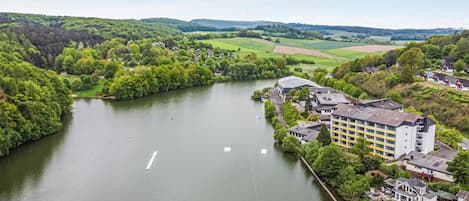 Un hôtel situé au bord de la rivière, doté d’un bâtiment moderne, d’un quai et entouré de verdure.