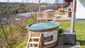 Jacuzzi amb escala de fusta, envoltat d'una terrassa i vista a un poble.