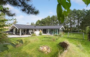A modern house with a large deck, a fire pit, and a soccer goal in the yard. - Stunning home in Knebel with sauna (Knebel)