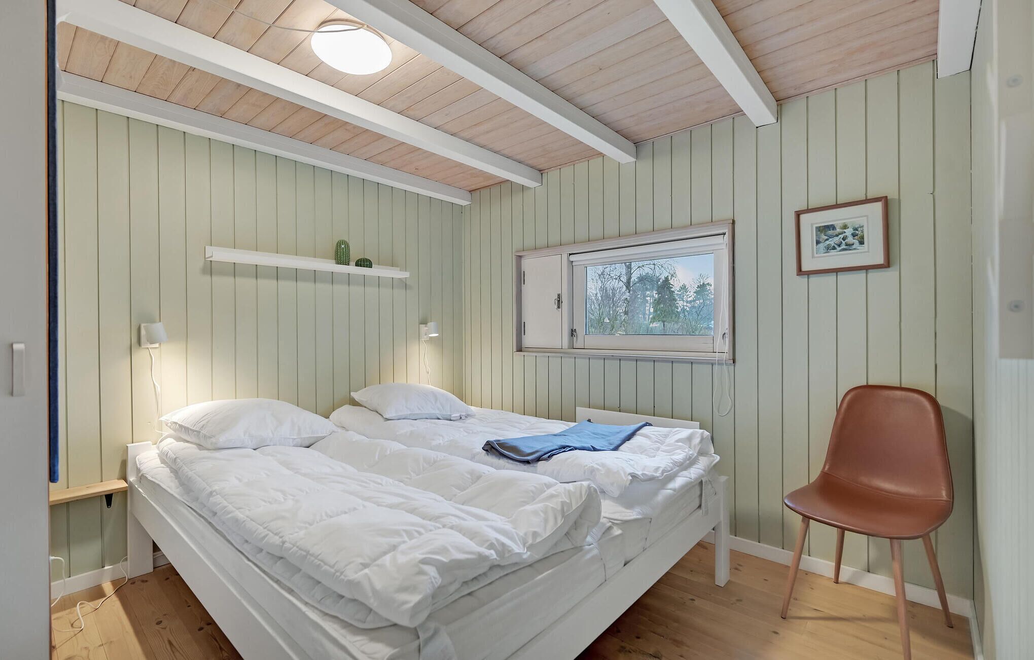Een kamer met twee bedden, een raam, een stoel en een plank met planten.