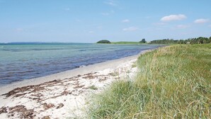 Een strand met helder water, een zandstrand en grasduinen.