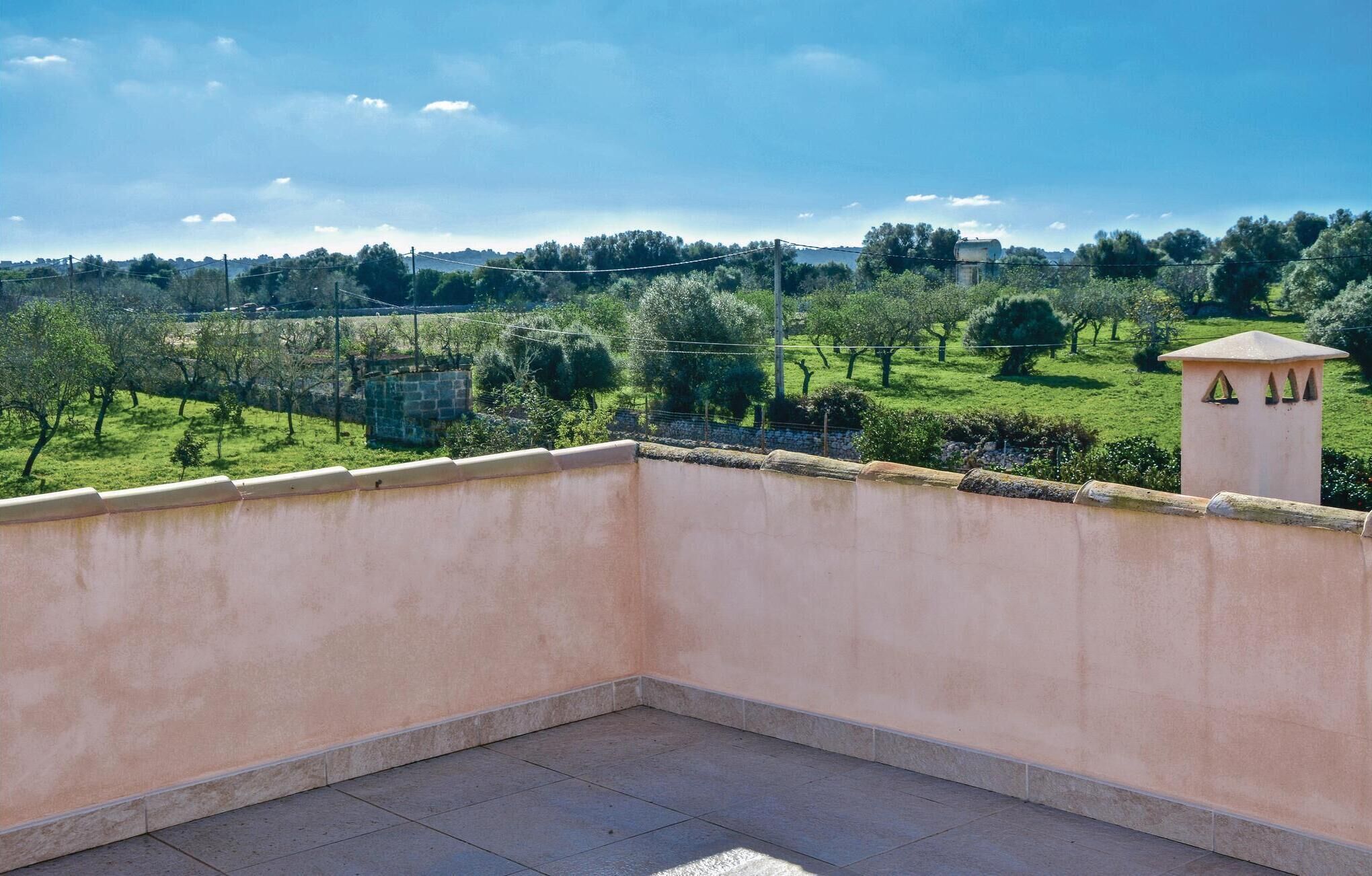 A balcony with a view of a green landscape and a stone structure in the distance.